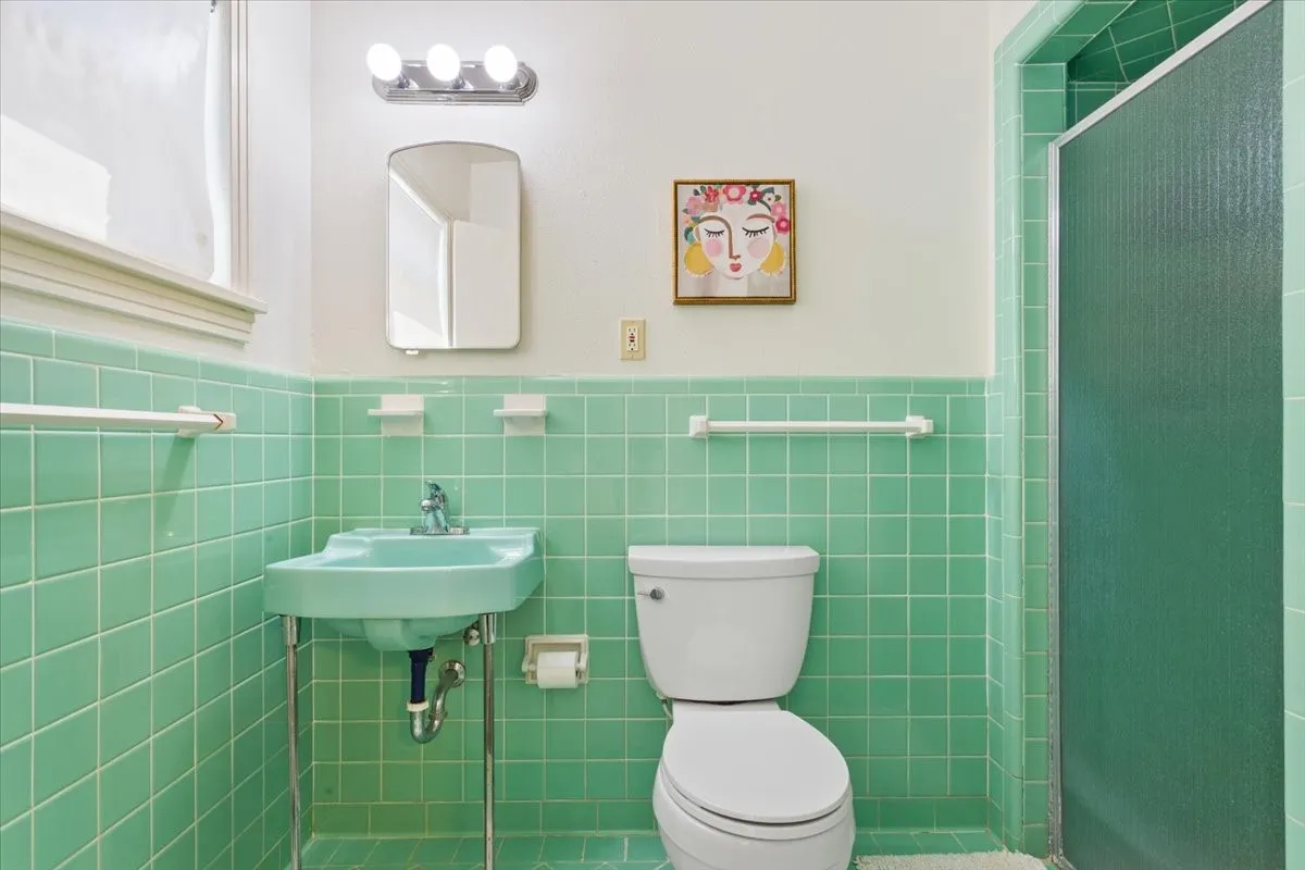 Bathroom featuring wainscoting, a shower stall, and tile walls