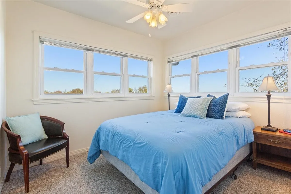 Carpeted bedroom featuring ceiling fan and baseboards