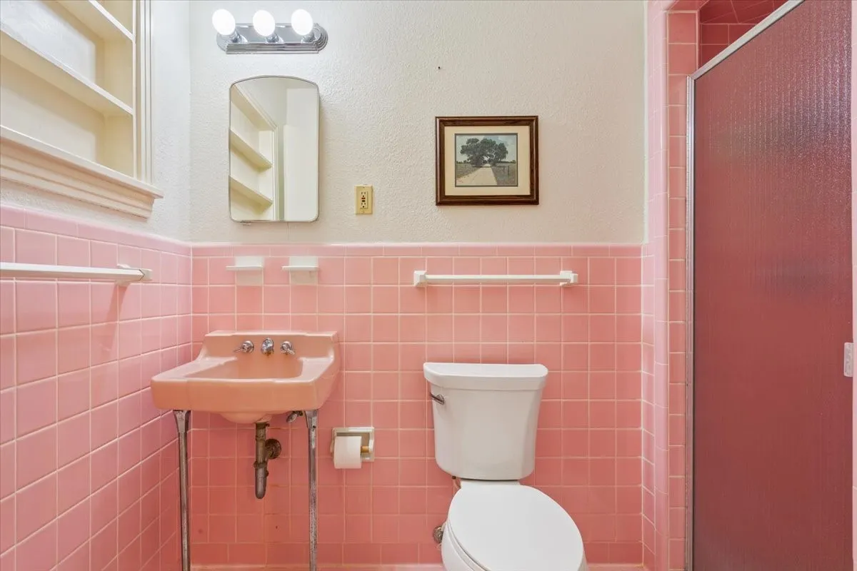 Bathroom with wainscoting, a stall shower, a textured wall, and tile walls