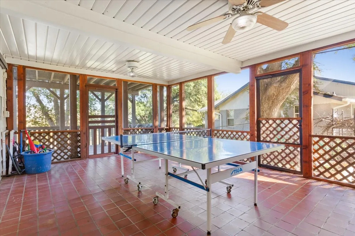 Recreation room featuring tile patterned floors, a wall of windows, ceiling fan, and a wooden ceiling with exposed beams