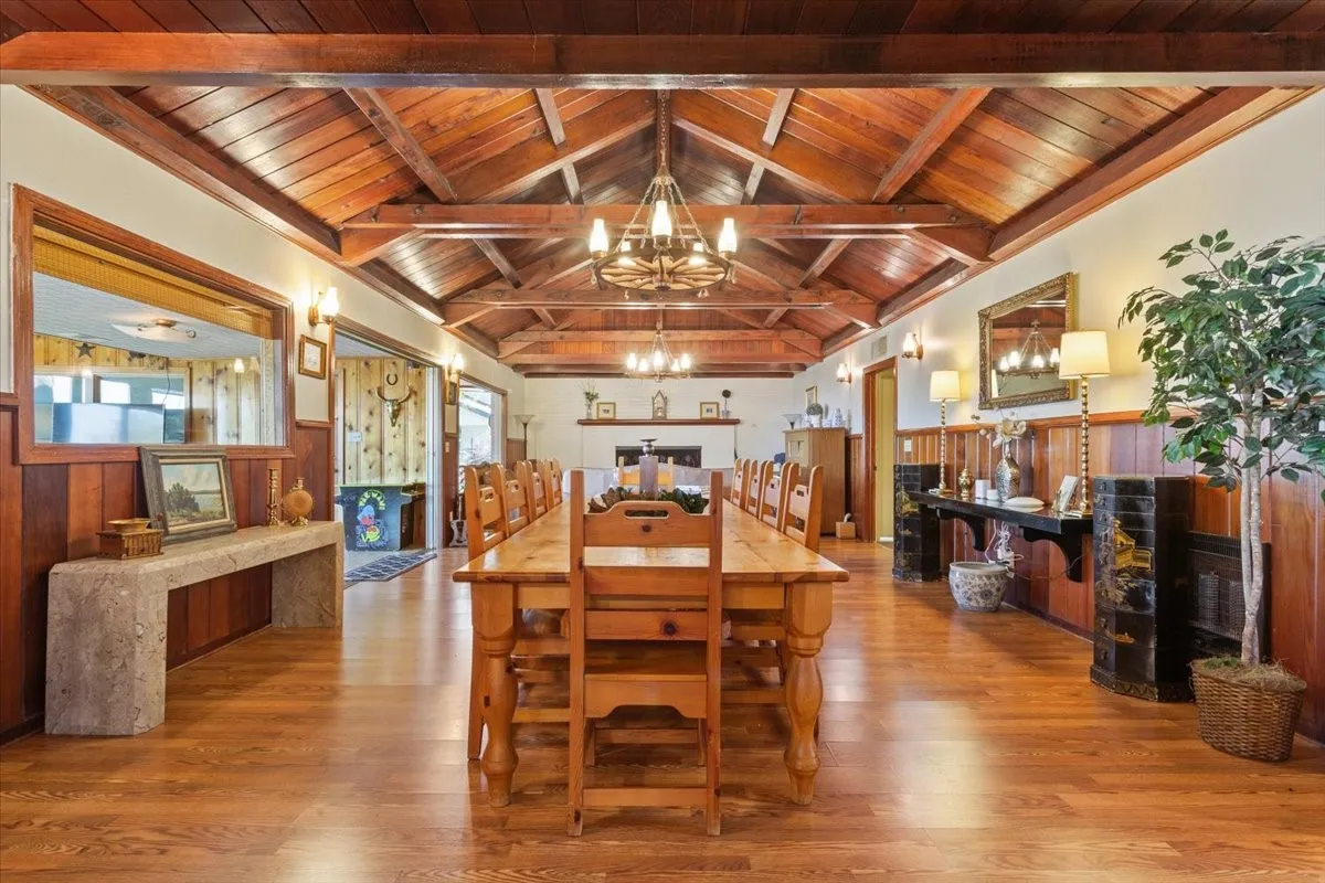 Dining room featuring a wainscoted wall, wooden ceiling, wooden walls, wood finished floors, and a chandelier
