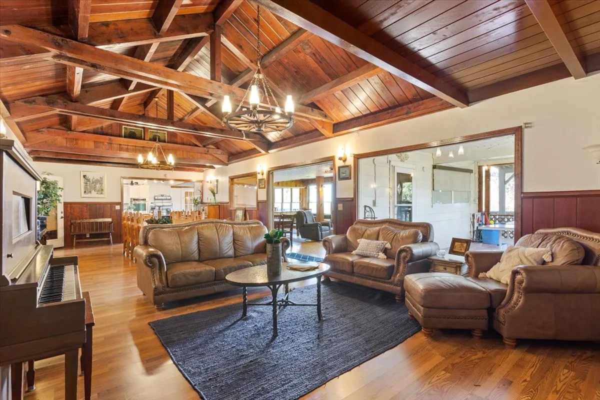 Living area featuring wainscoting, wood ceiling, a chandelier, and wood finished floors