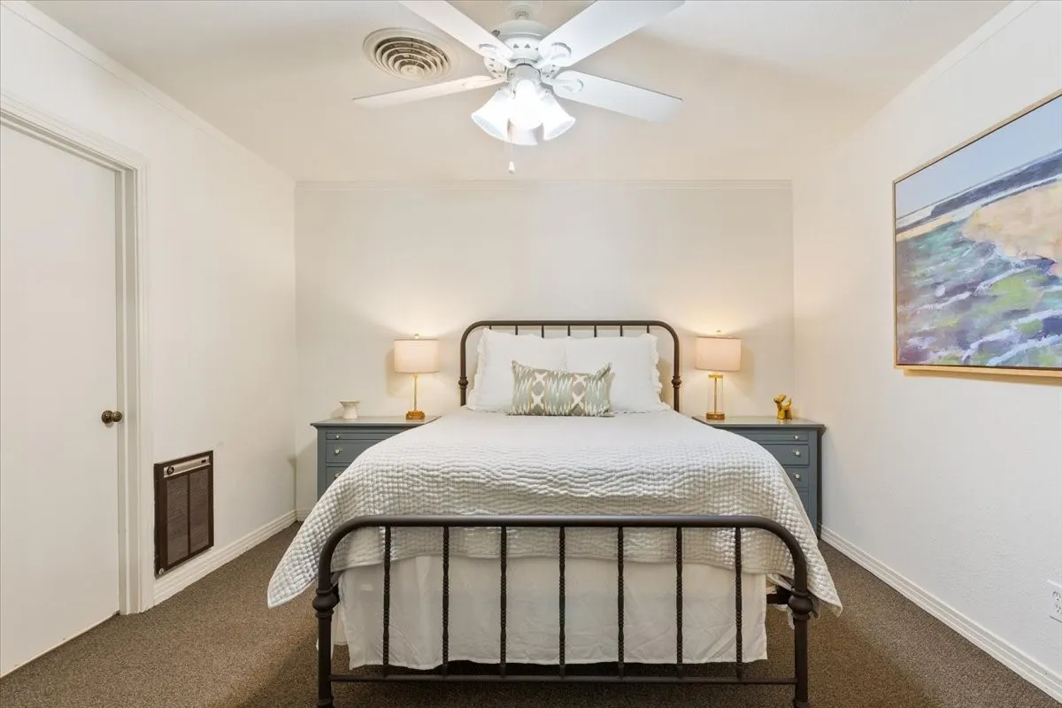 Carpeted bedroom featuring ceiling fan, heating unit, and crown molding