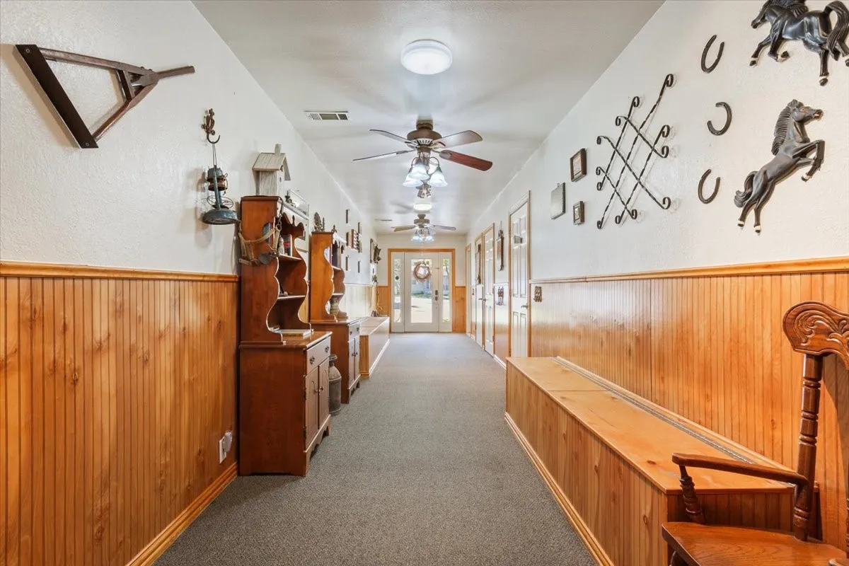 Hall with wood walls, dark carpet, wainscoting, and a textured wall