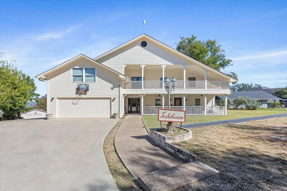 View of front of property with a porch, a front yard, concrete driveway, and an attached garage