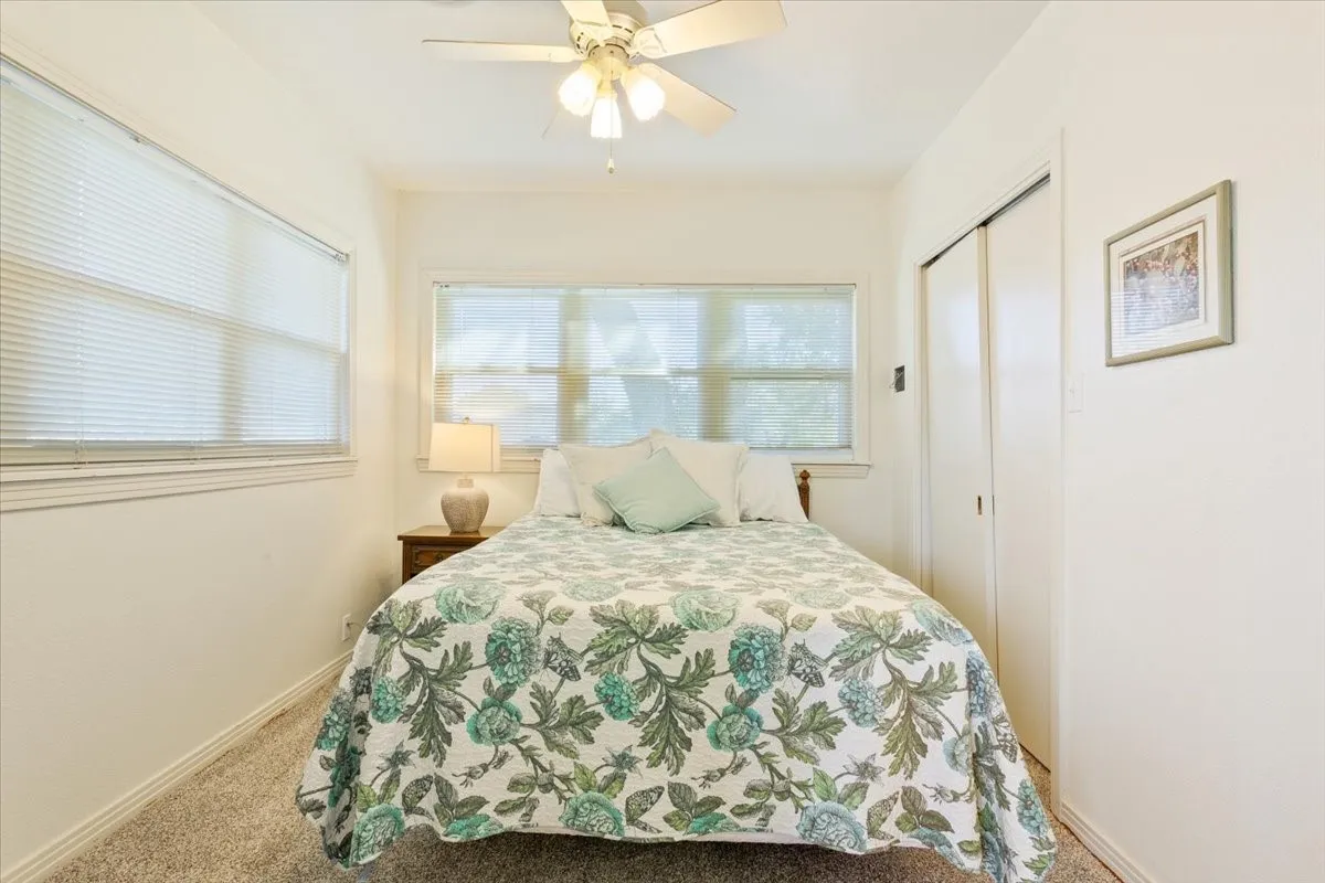 Carpeted bedroom with ceiling fan and a closet