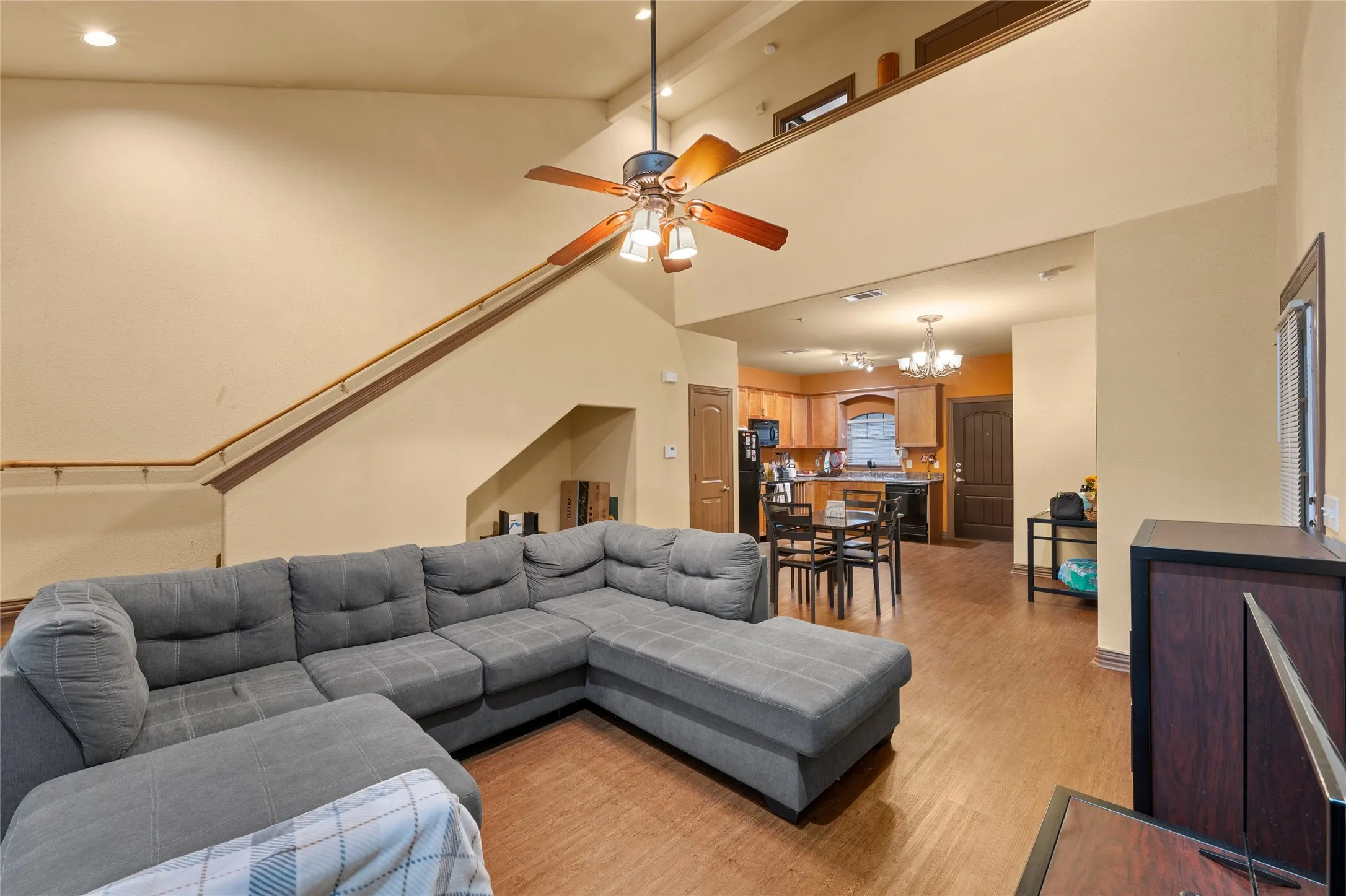 Living area featuring light wood finished floors, a towering ceiling, ceiling fan, a chandelier, and recessed lighting