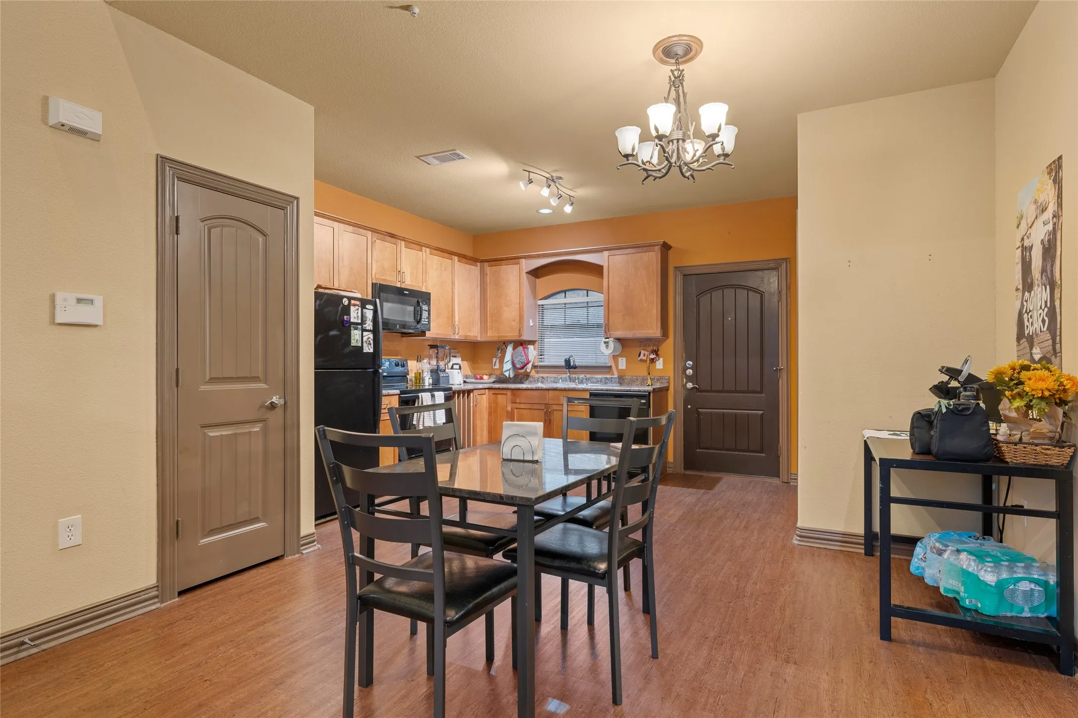 Dining space with light wood-style floors, a chandelier, and track lighting