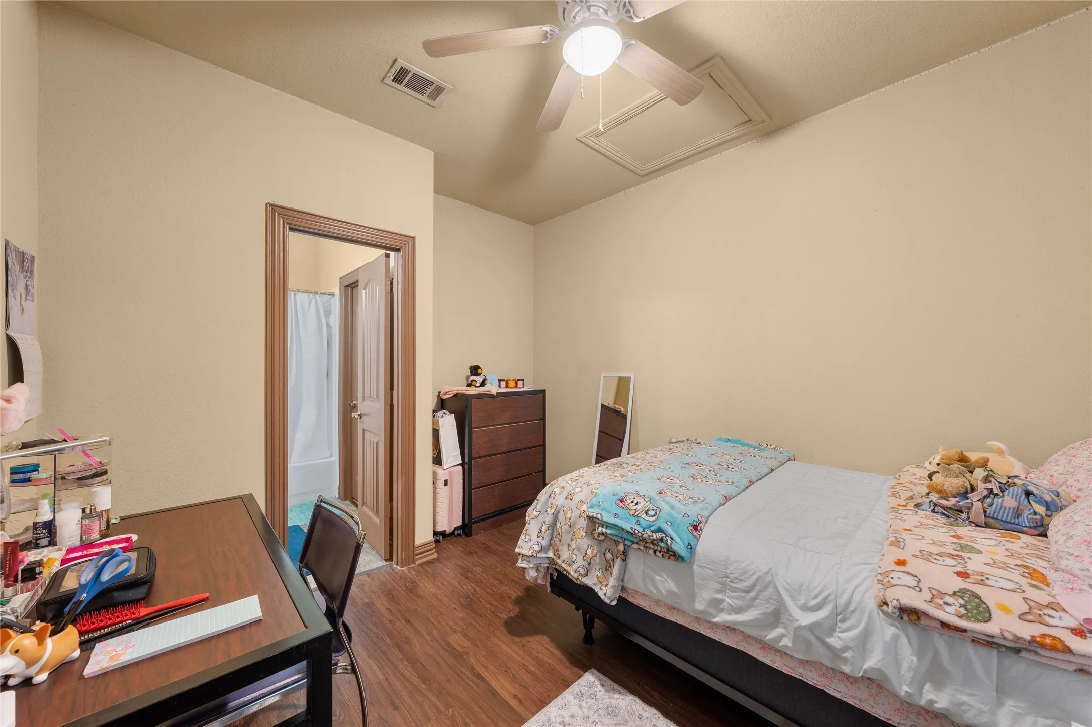 Bedroom featuring attic access, dark wood-type flooring, ceiling fan, and a desk