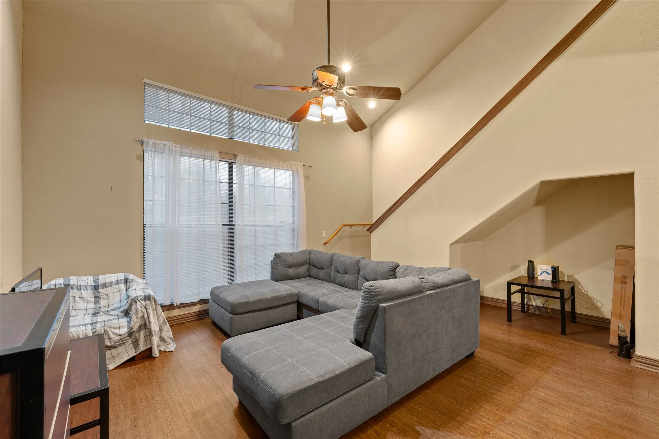 Living area featuring a towering ceiling, light wood-type flooring, and stairway