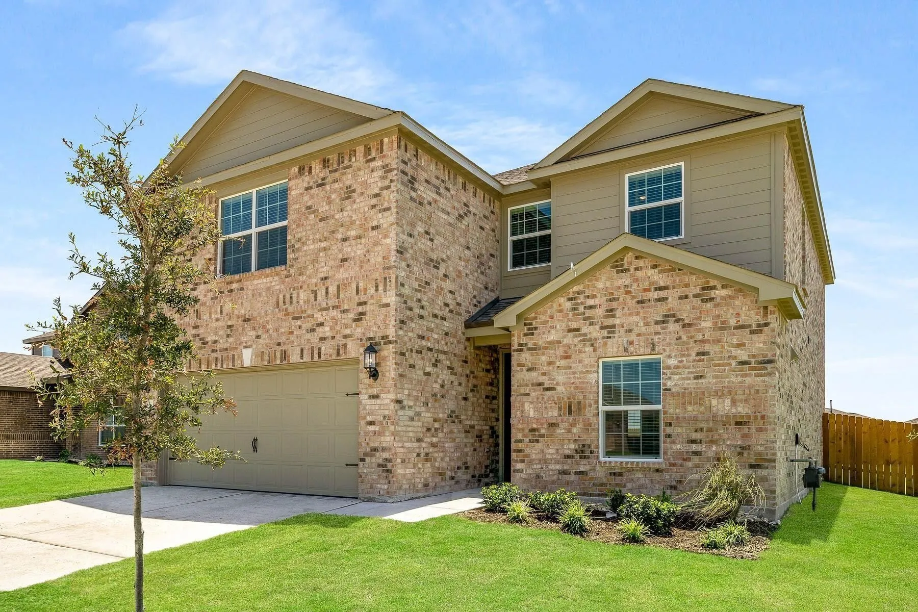 Traditional home with an attached garage, brick siding, and driveway