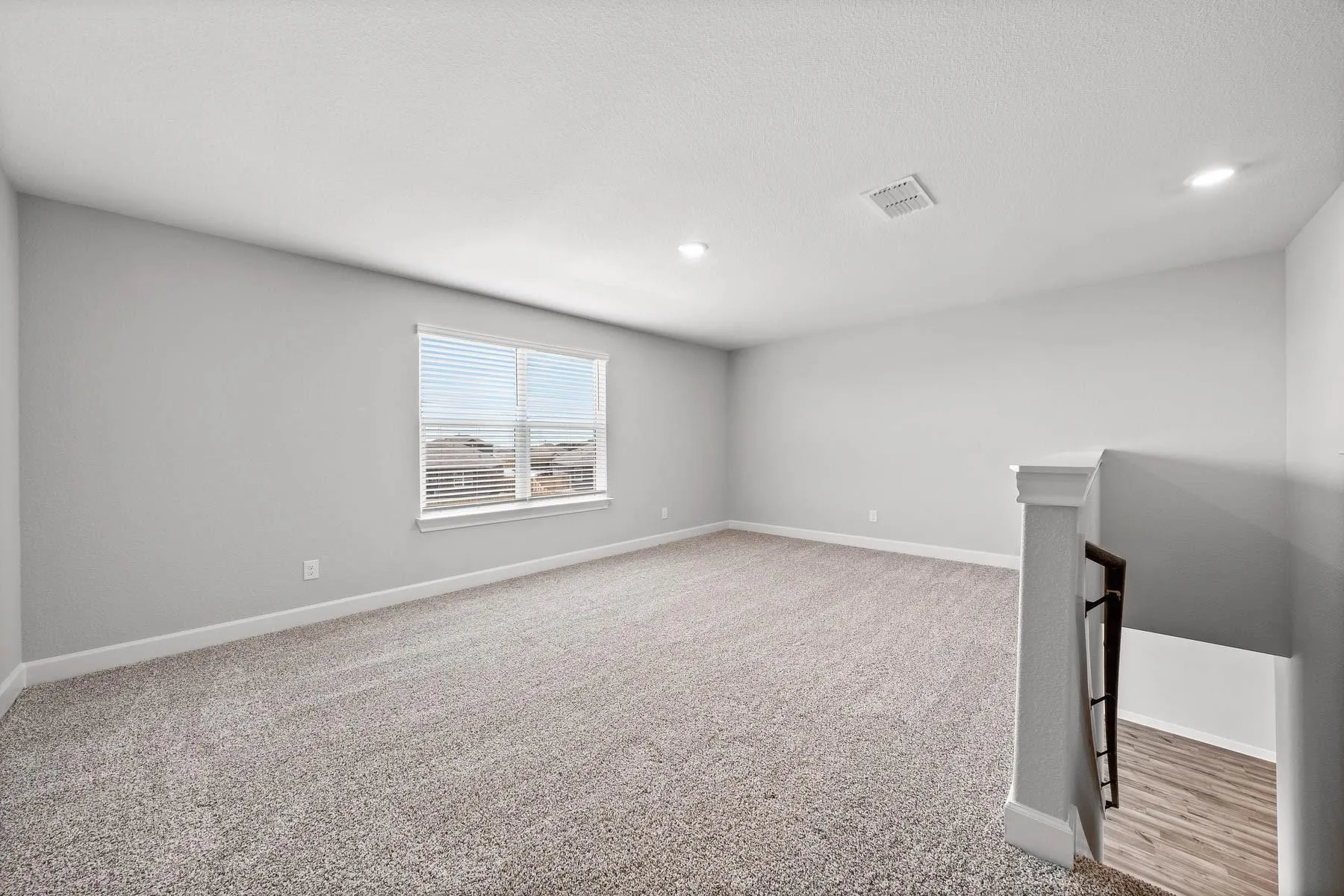 Empty room with light colored carpet and baseboards