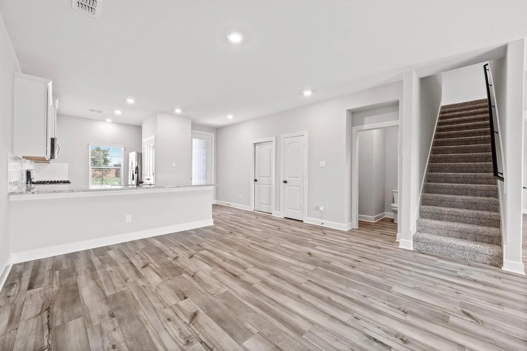Unfurnished living room featuring light wood finished floors, stairway, and recessed lighting