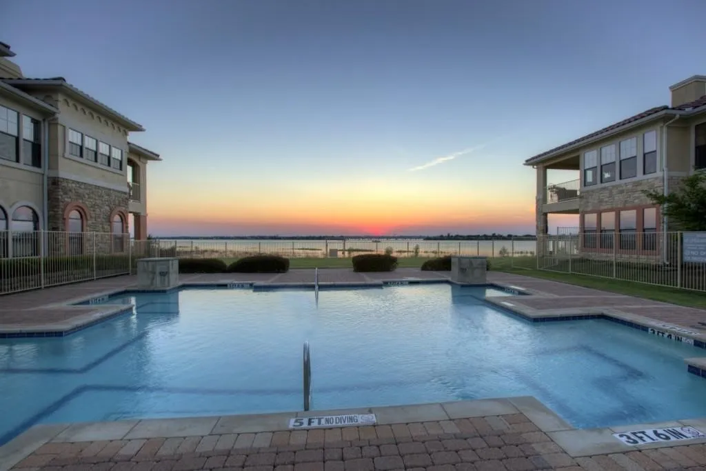 Pool at dusk featuring a community pool, a patio, and a balcony