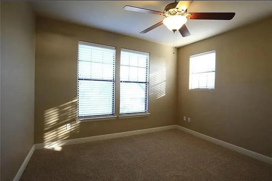 Carpeted spare room featuring baseboards and a ceiling fan