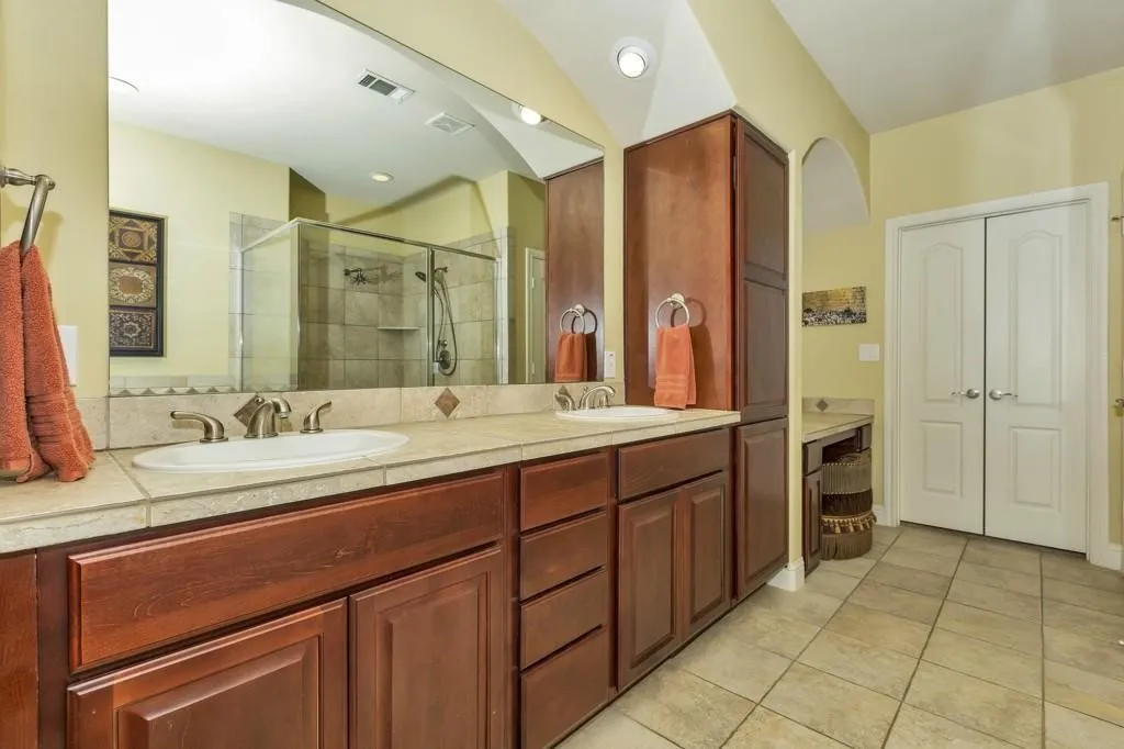 Full bath featuring double vanity, a shower stall, and light tile patterned floors