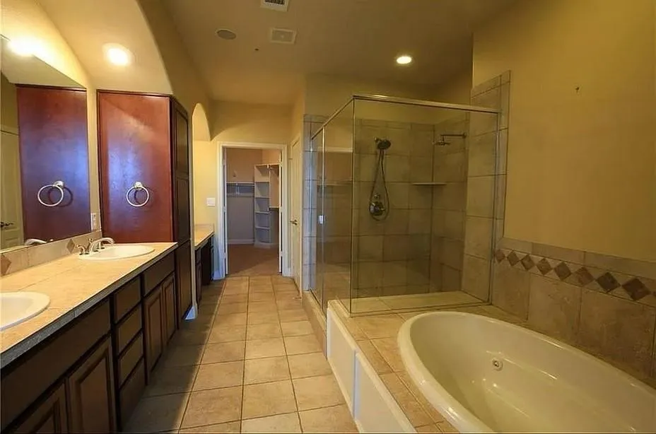 Bathroom with double vanity, a whirlpool tub, a spacious closet, light tile patterned floors, and a shower stall