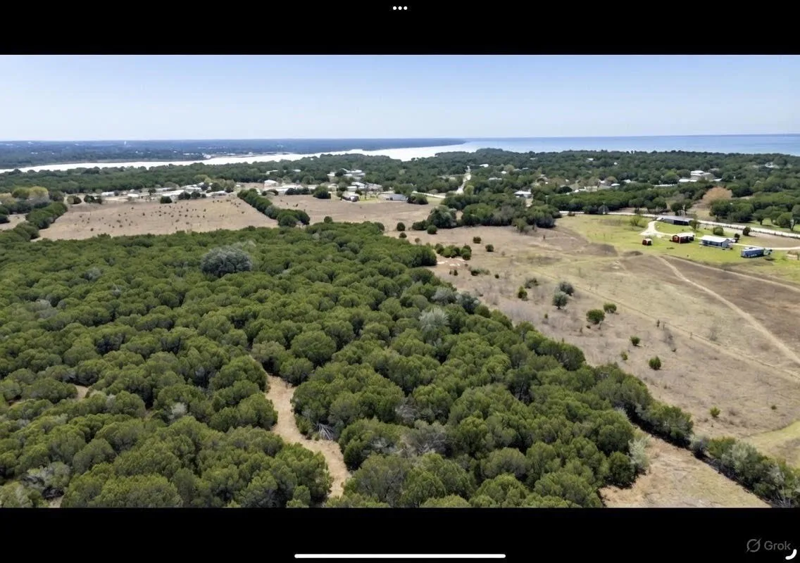 Overview of rural landscape with a nearby body of water and a heavily wooded area
