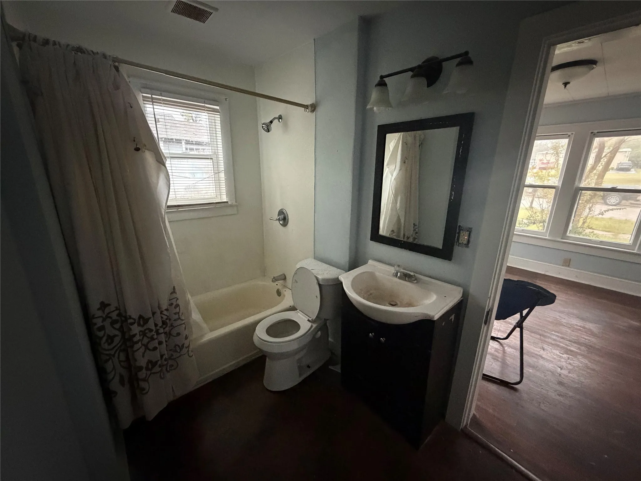 Bathroom featuring shower / bath combination with curtain, vanity, and dark wood finished floors