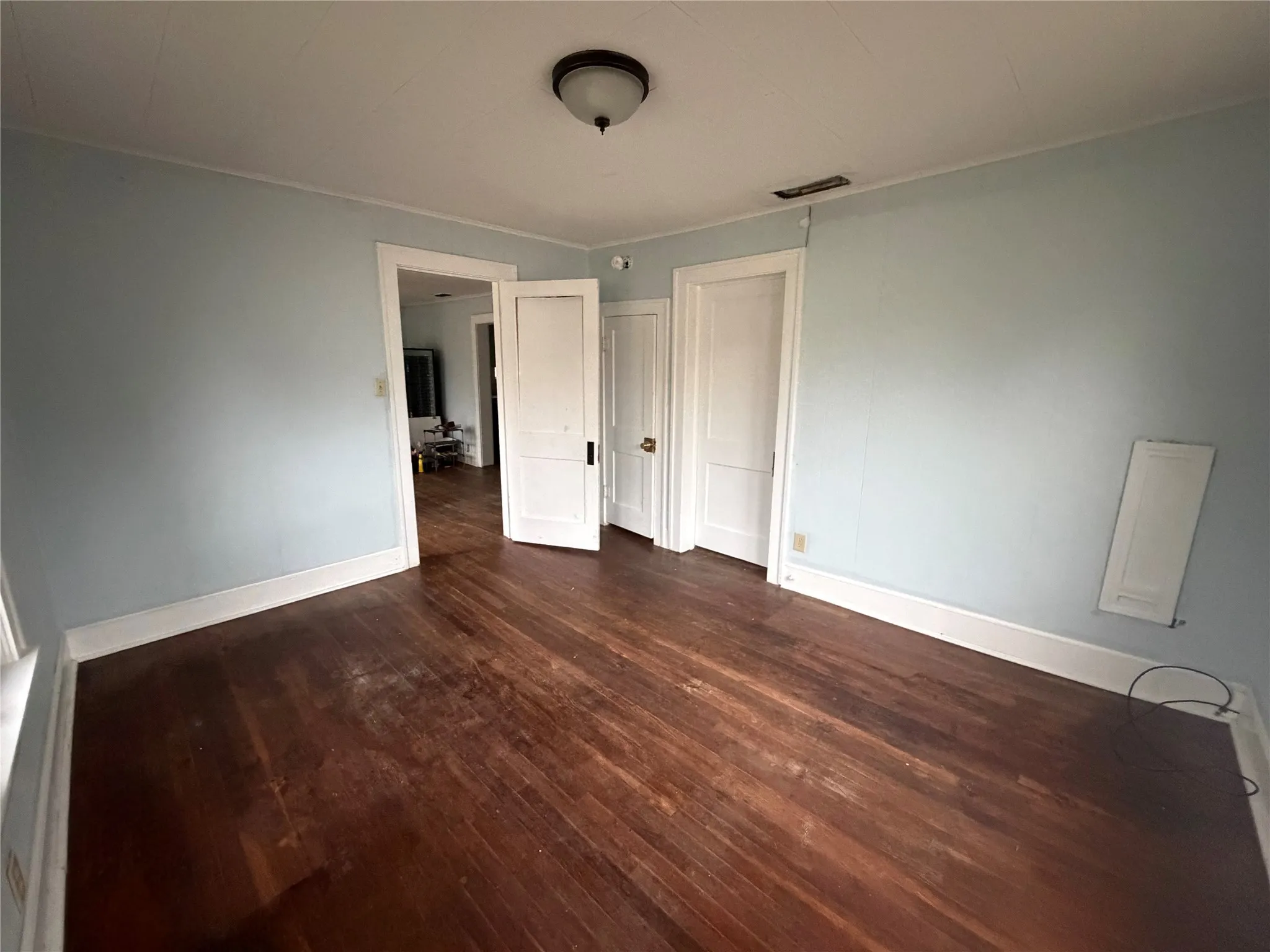 Unfurnished bedroom with dark wood-type flooring and baseboards