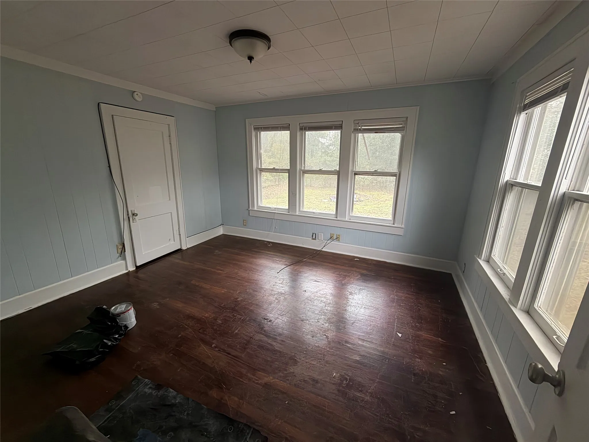 Empty room with ornamental molding and dark wood-type flooring