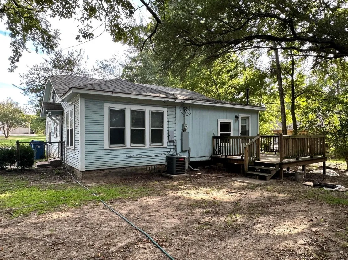 Back of house with a shingled roof and a wooden deck