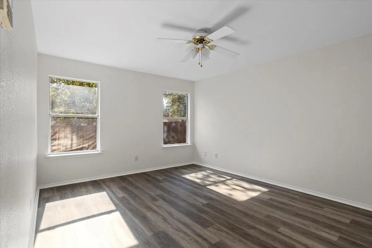Empty room with dark wood-style flooring and a ceiling fan