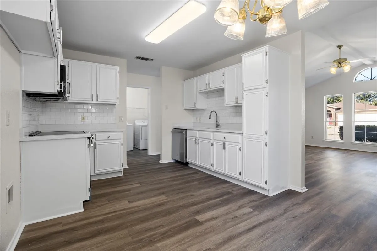 Kitchen featuring lofted ceiling, light countertops, decorative backsplash, and white cabinetry