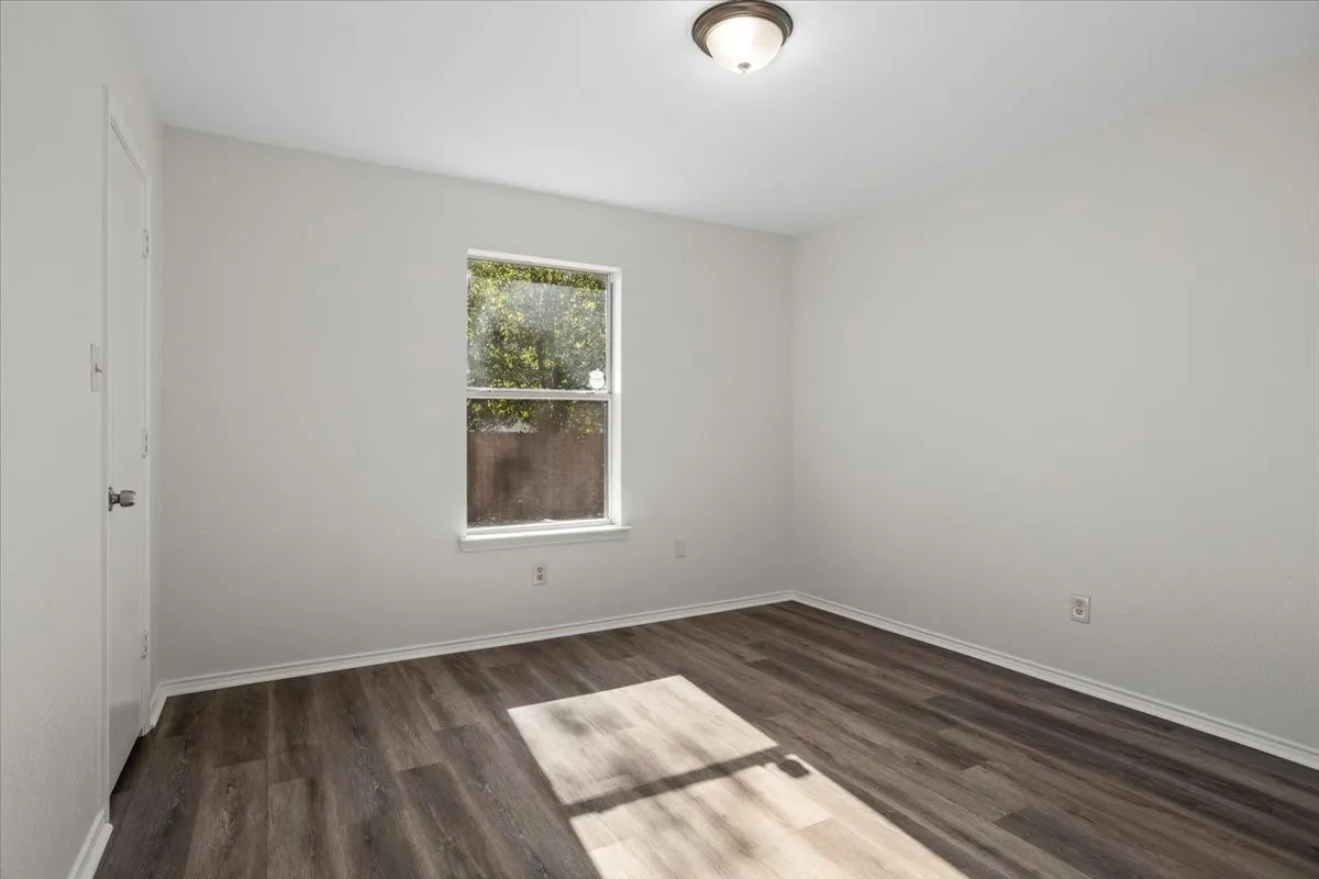 Empty room with dark wood-style flooring and baseboards