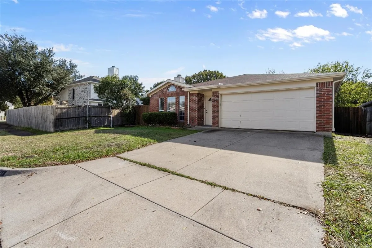 View of front facade with brick siding, concrete driveway, and an attached garage