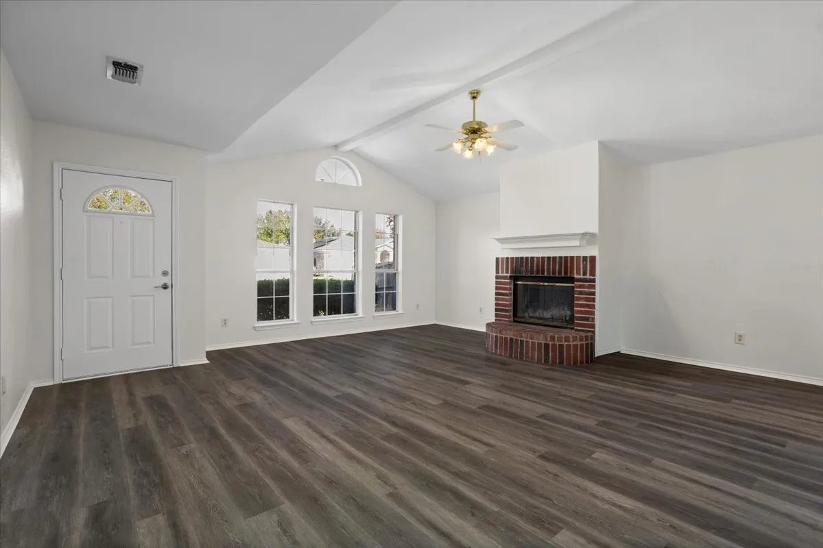 Unfurnished living room with dark wood-style floors, a fireplace, and ceiling fan