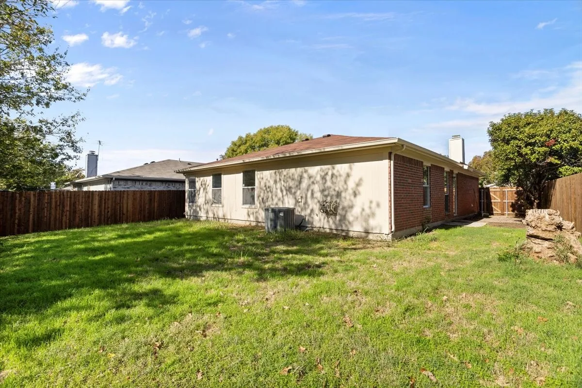 Back of house featuring a fenced backyard, brick siding, and a chimney