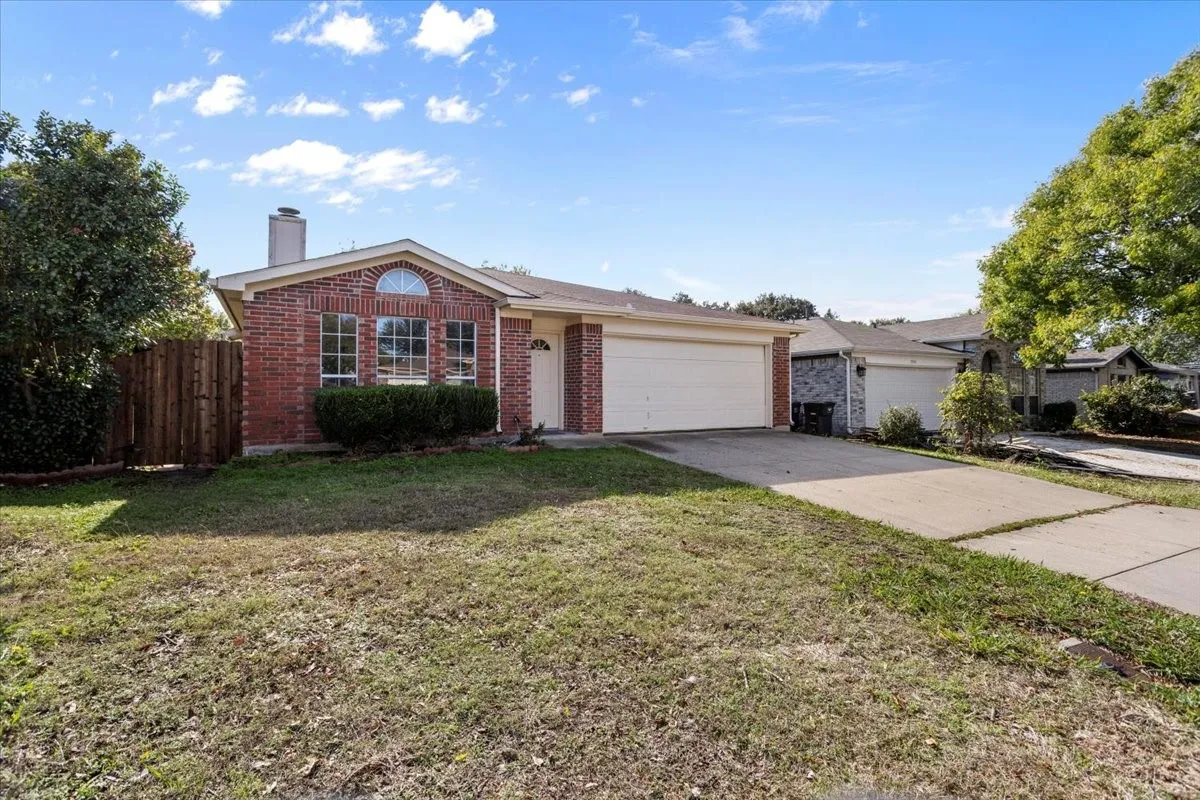 Single story home featuring brick siding, a chimney, concrete driveway, and an attached garage