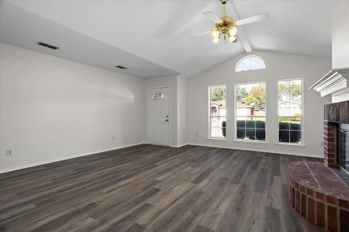 Unfurnished living room featuring a fireplace, a ceiling fan, and dark wood finished floors