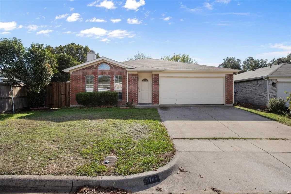 Single story home featuring brick siding, concrete driveway, a chimney, and an attached garage