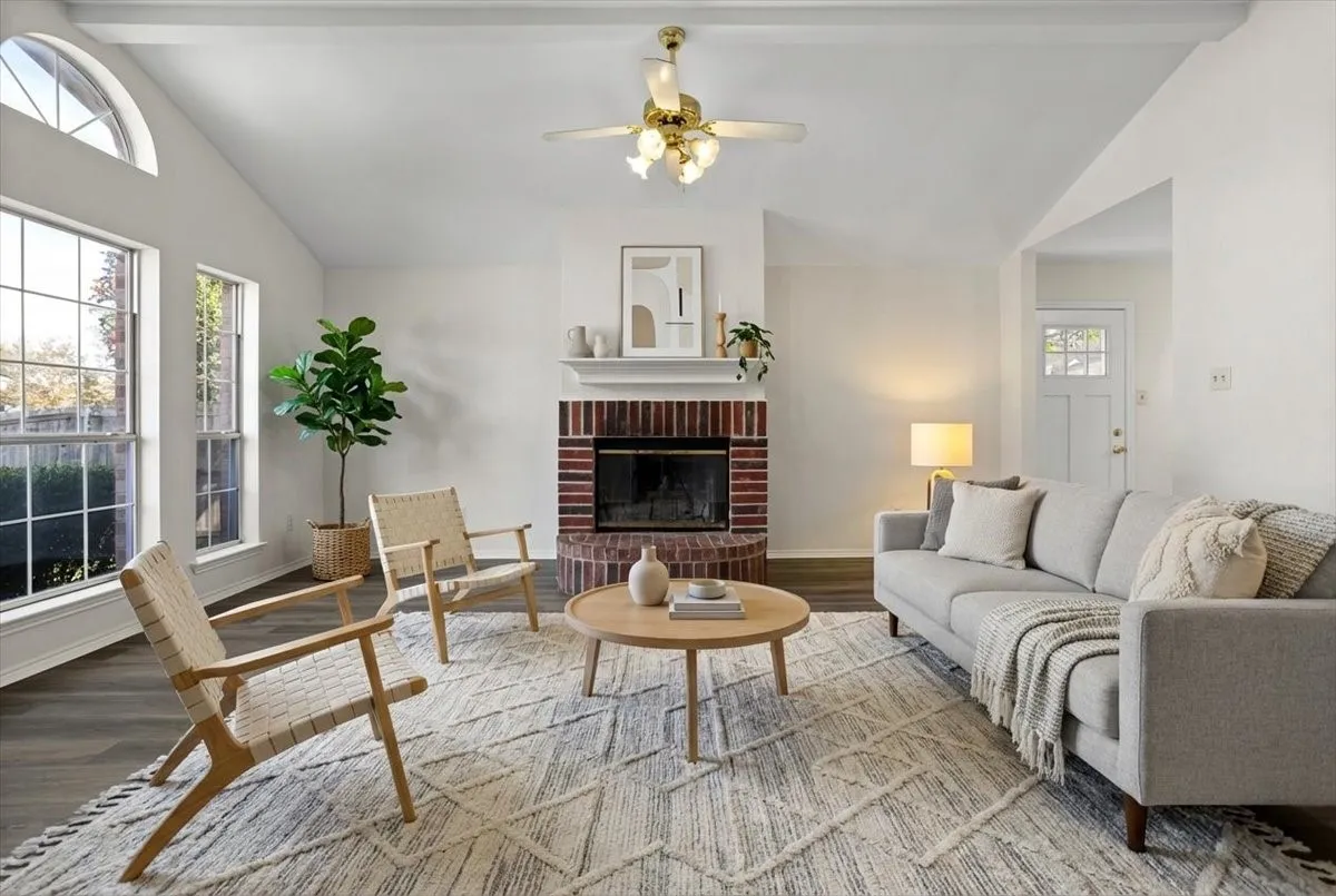 Living area with a fireplace, plenty of
natural light, wood finished floors, and a ceiling fan- Virtually staged