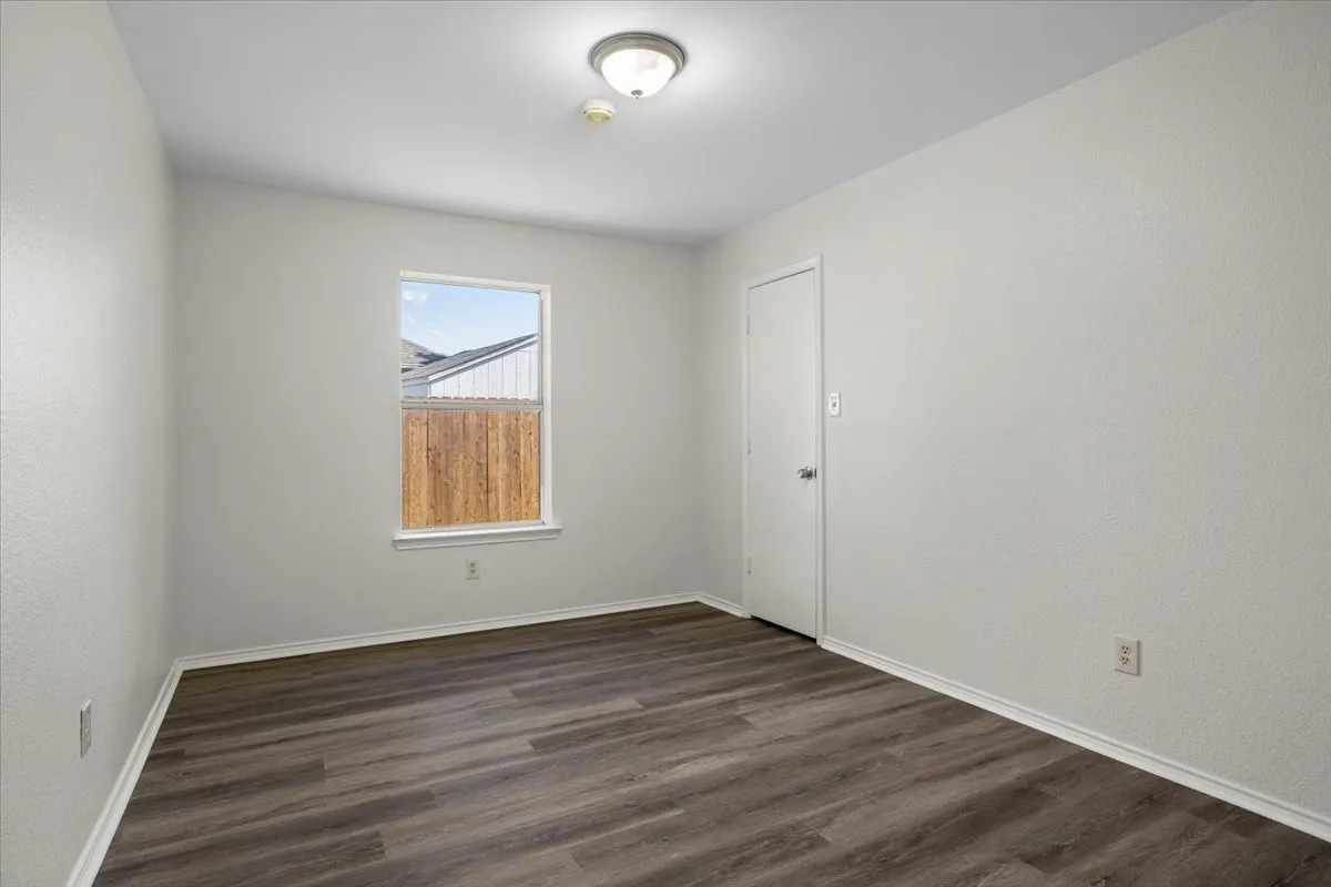 Unfurnished room with dark wood-type flooring and baseboards