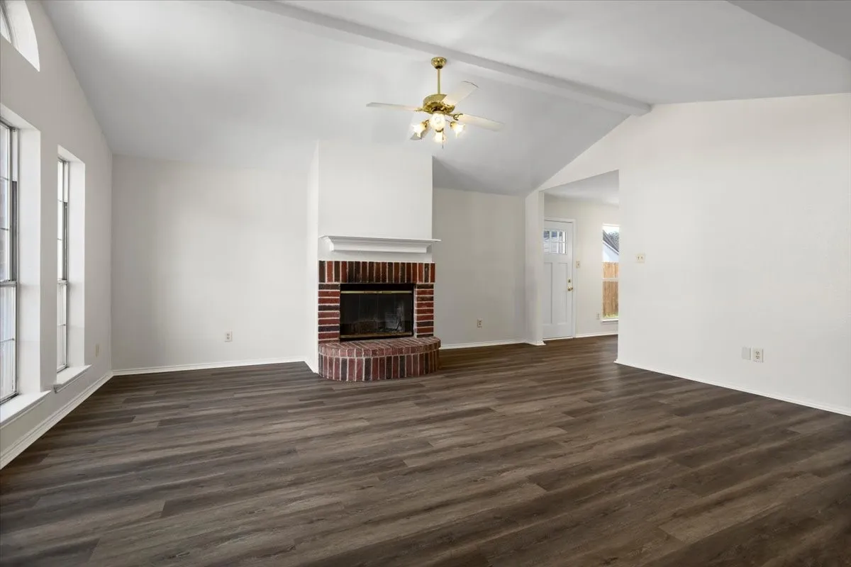 Unfurnished living room with dark wood-style flooring, a fireplace, and ceiling fan