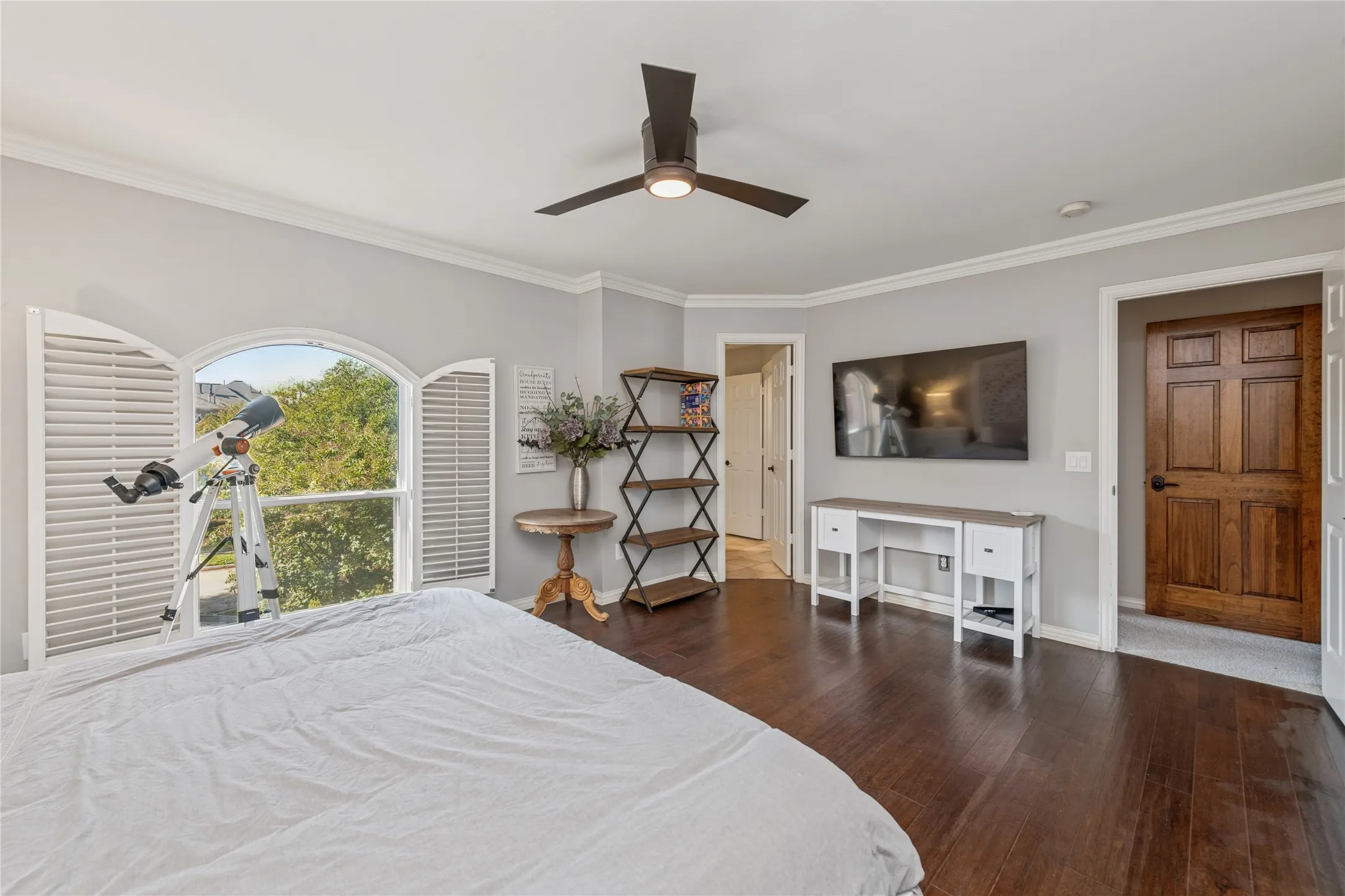 Bedroom featuring dark wood finished floors, crown molding, and a ceiling fan