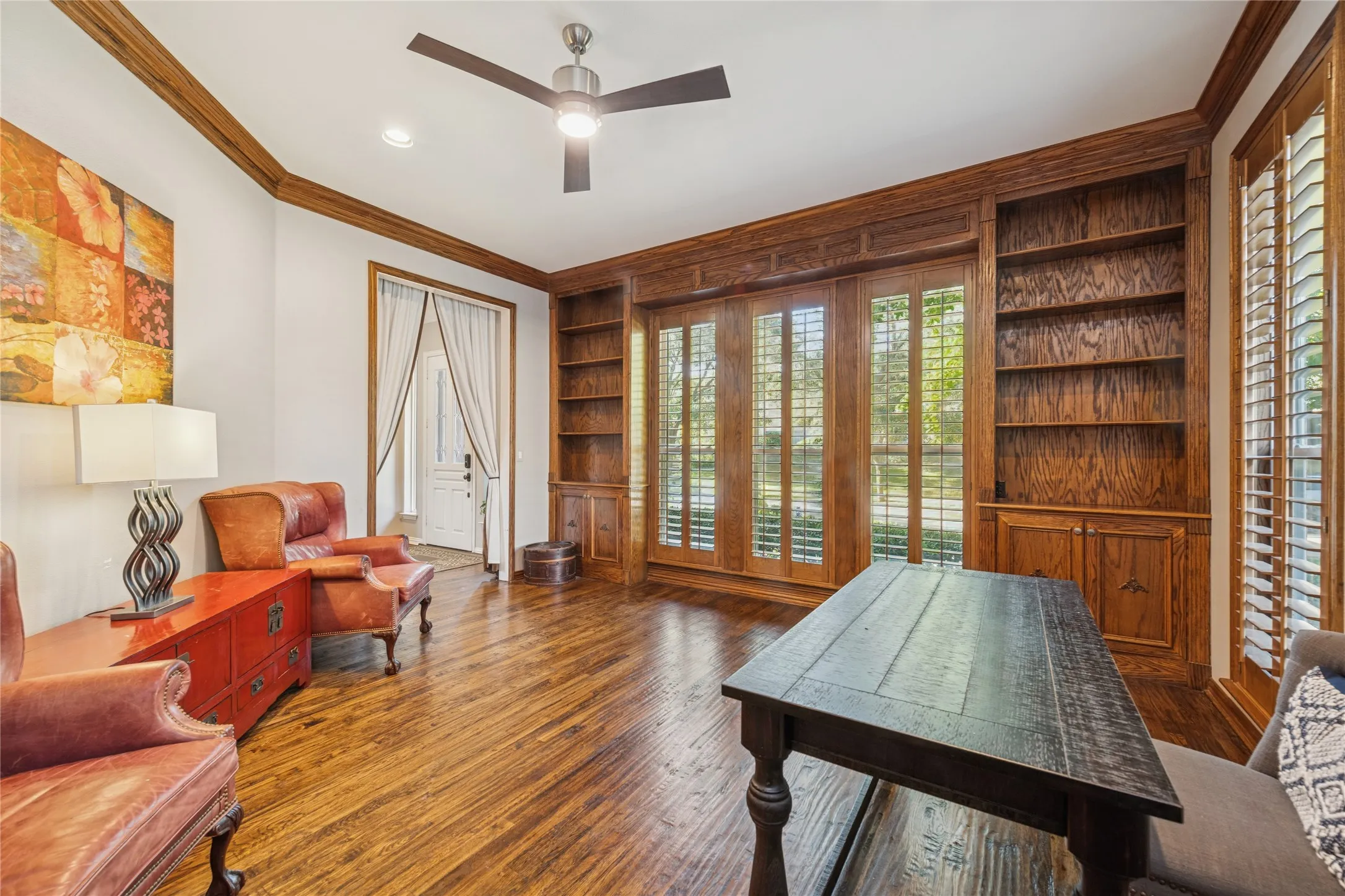 Office space with built in shelves, ornamental molding, hardwood / wood-style flooring, and ceiling fan