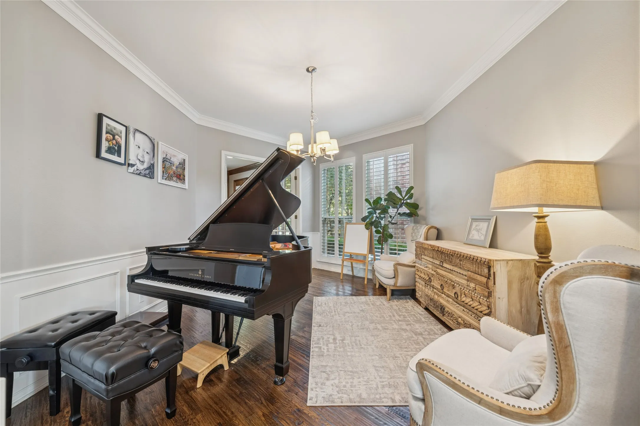 Living area with crown molding, dark wood-style flooring, a chandelier, wainscoting, and a decorative wall