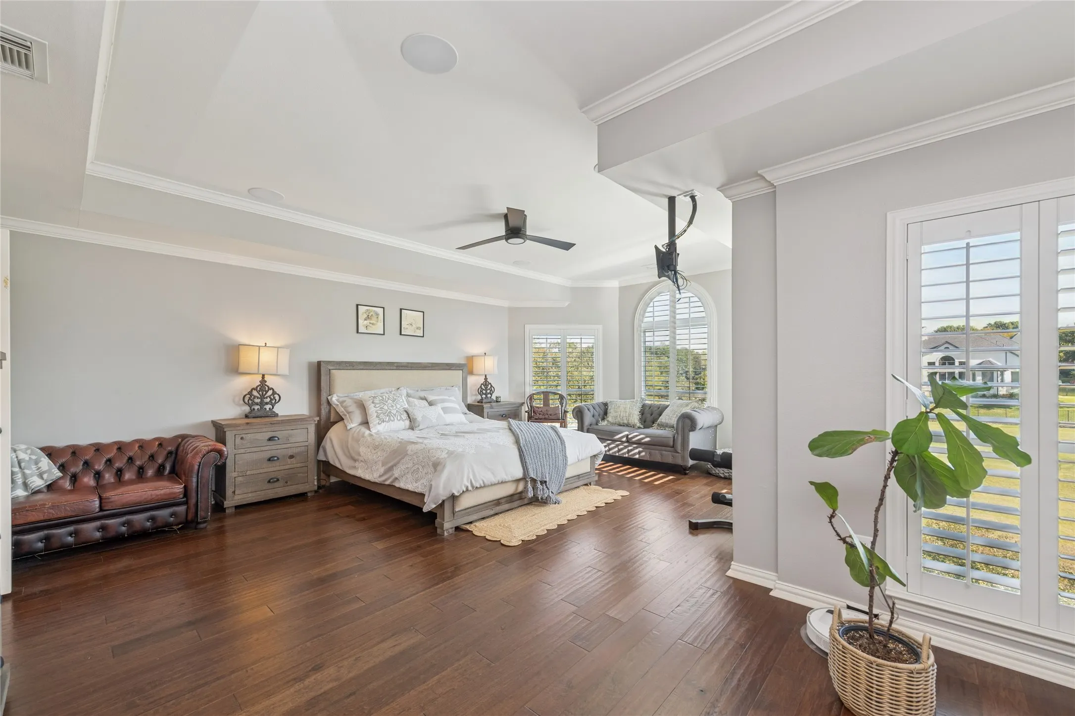 Bedroom featuring dark wood finished floors, ornamental molding, and ceiling fan