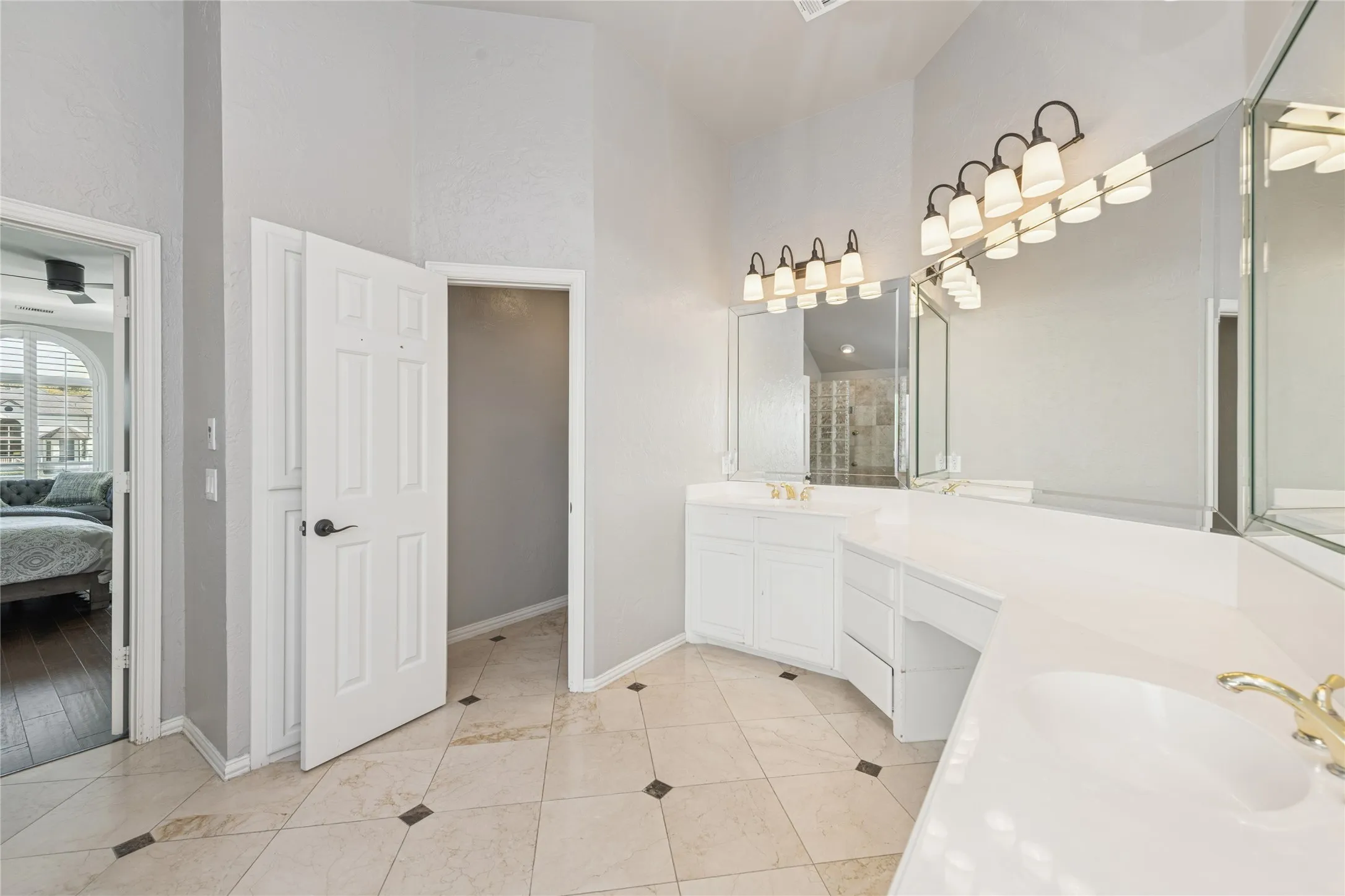 Full bathroom featuring two vanities, double vanity, connected bathroom, a stall shower, and light tile patterned floors