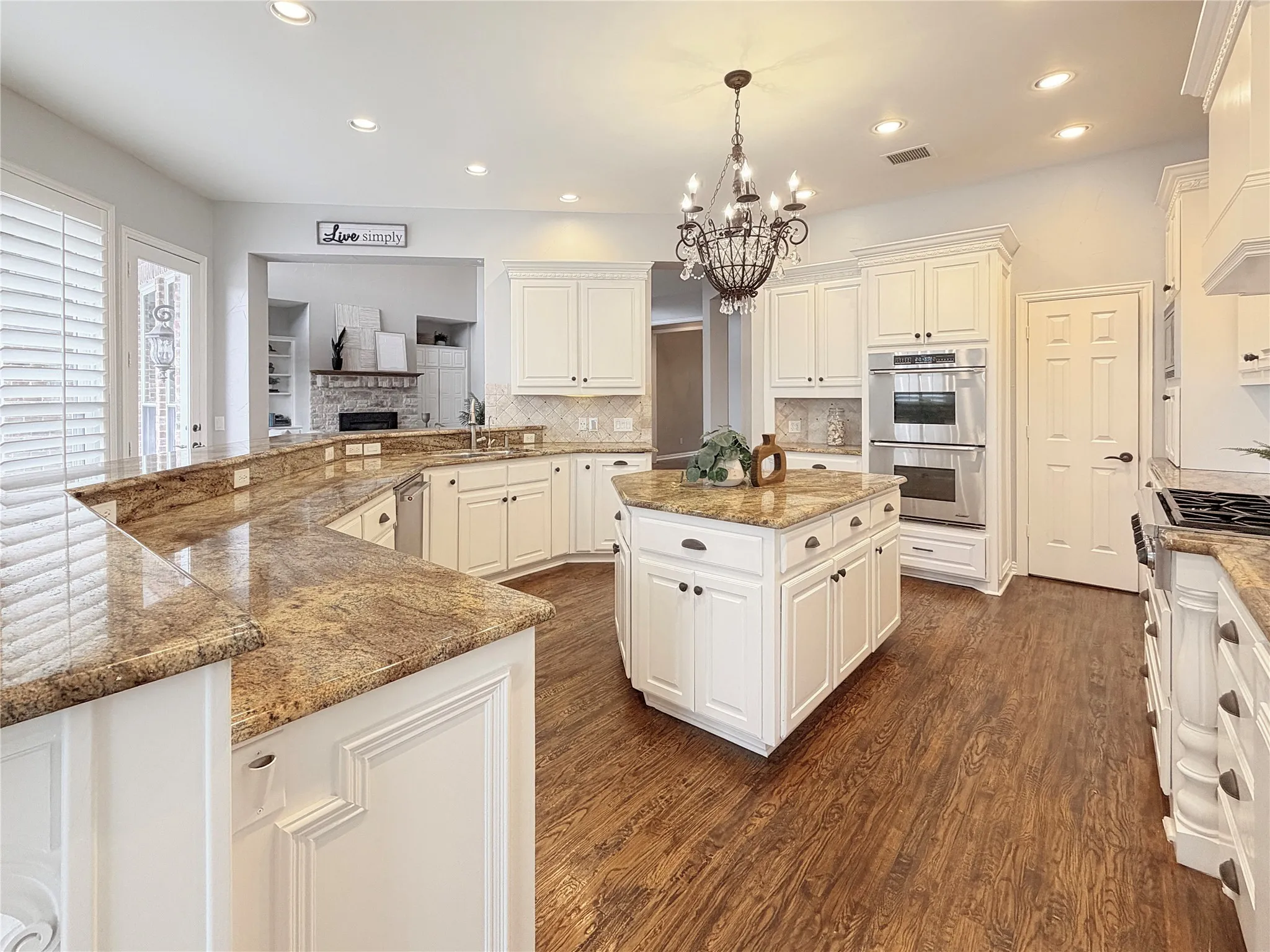 Kitchen featuring a center island, light stone countertops, stainless steel appliances, pendant lighting, and dark wood-style flooring