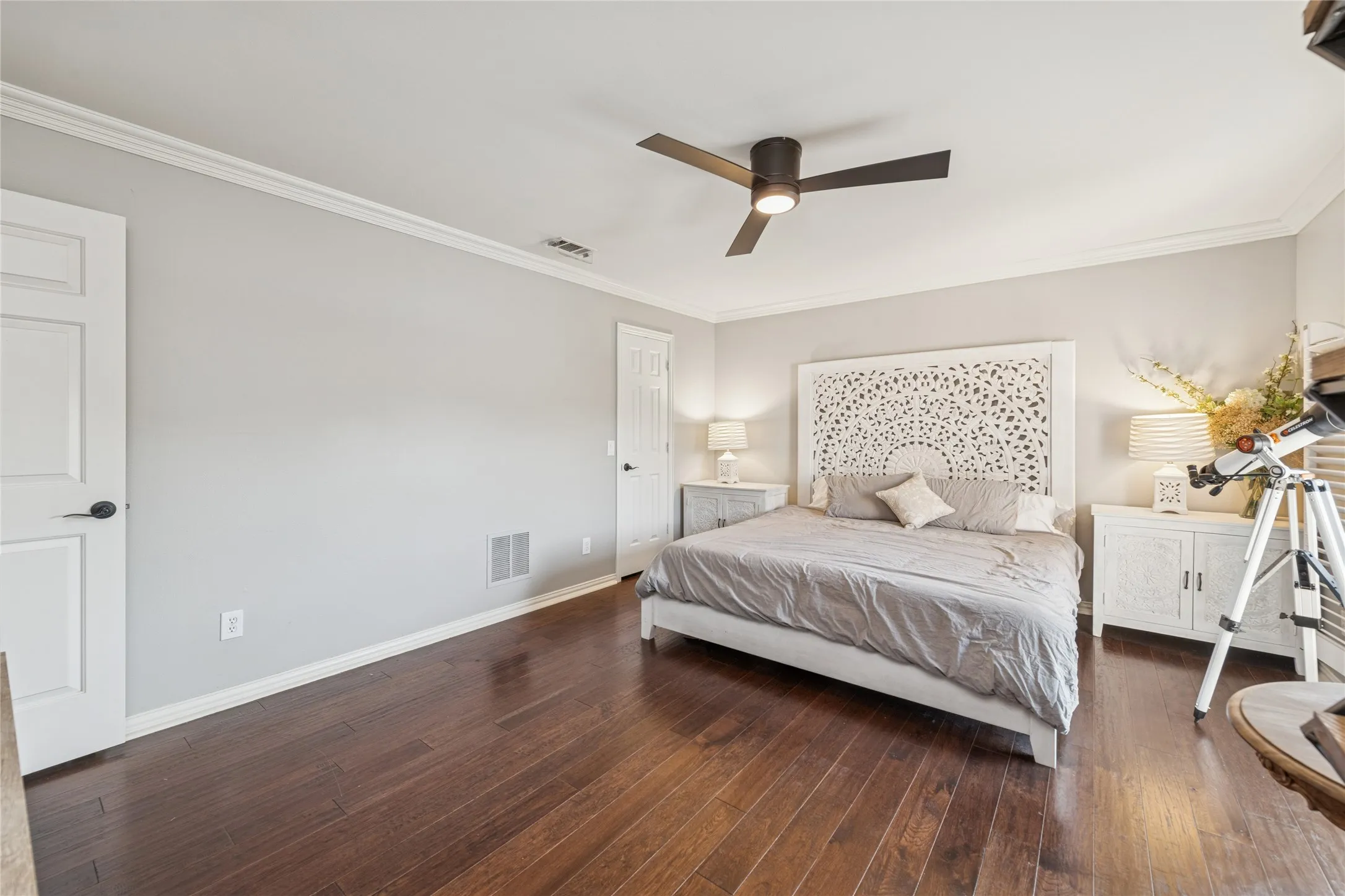 Bedroom with ornamental molding, dark wood-style floors, and a ceiling fan