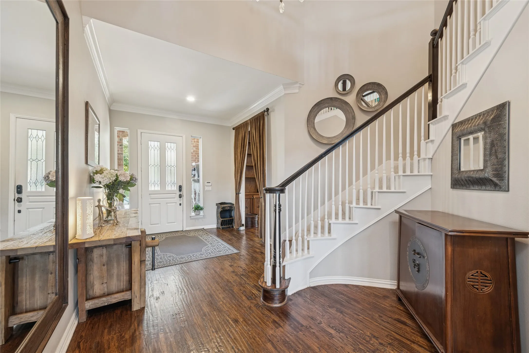 Entrance foyer featuring dark wood-type flooring, crown molding, and stairway