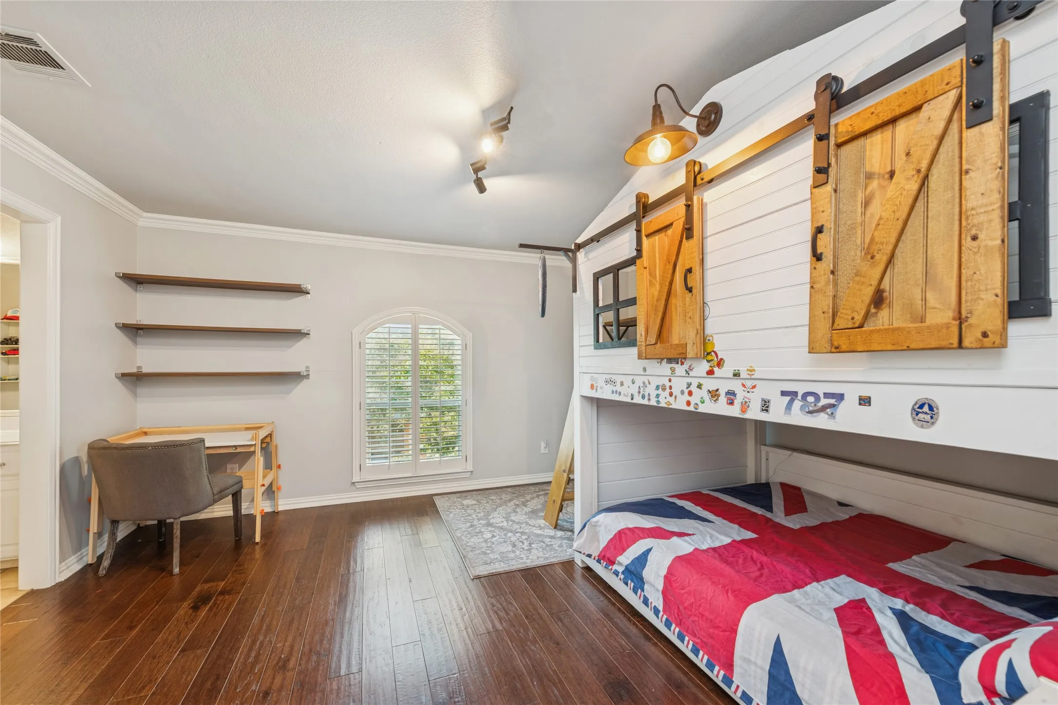 Bedroom featuring an office area, dark wood-type flooring, a barn door, and crown molding