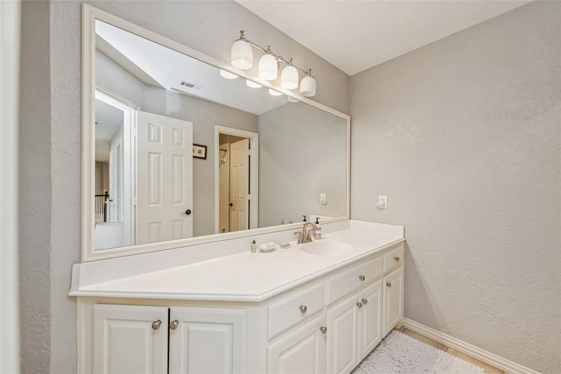 Bathroom featuring a textured wall and vanity