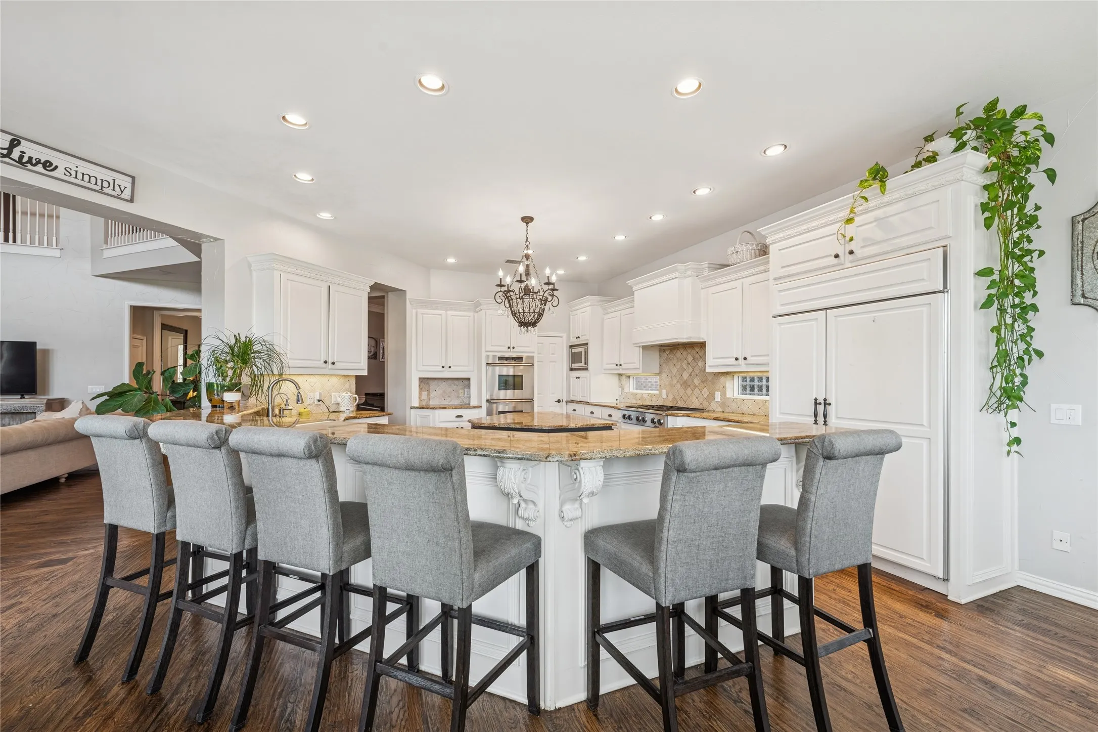 Kitchen featuring light stone countertops, white cabinets, backsplash, hanging light fixtures, and recessed lighting