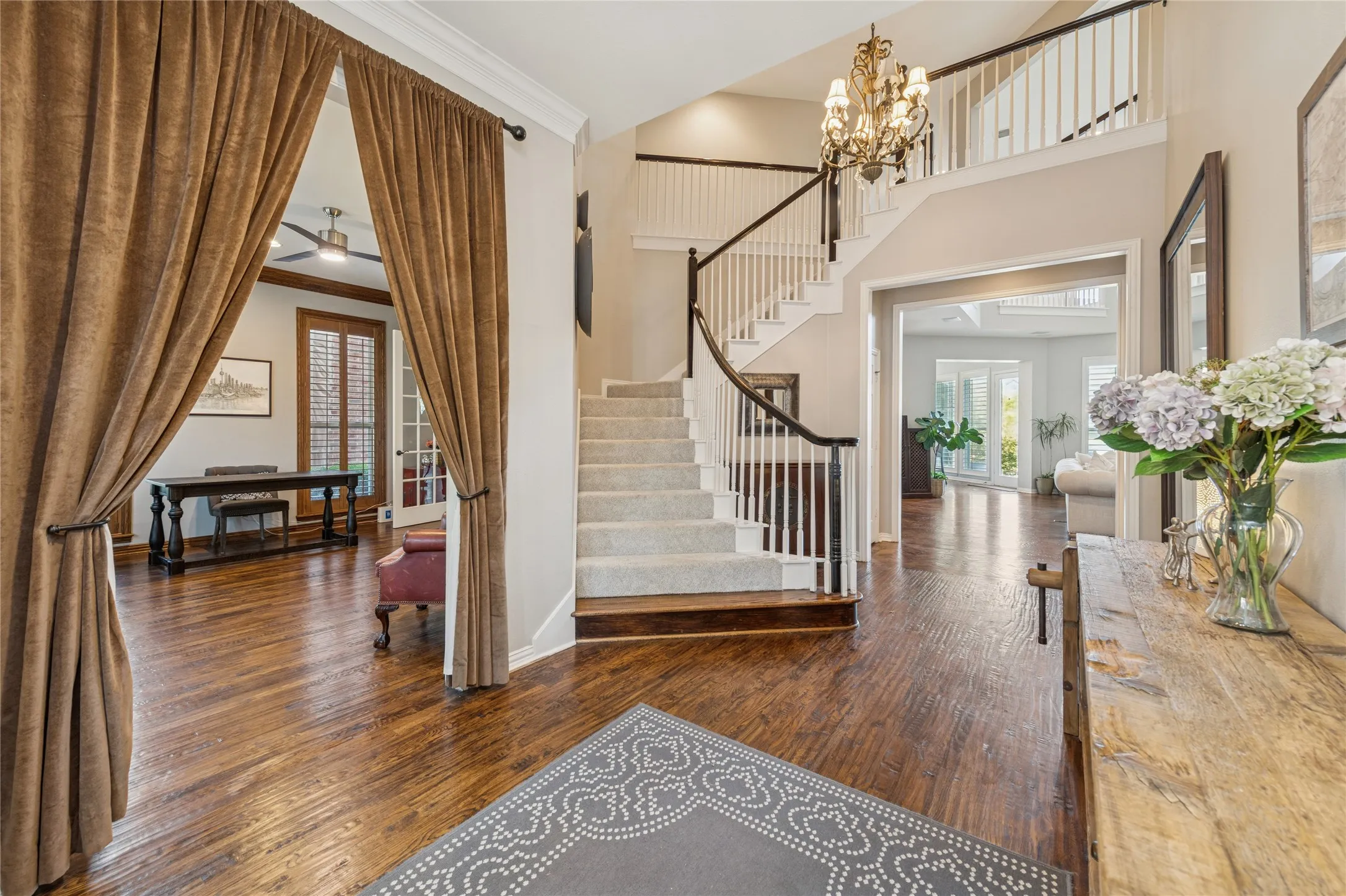 Foyer featuring dark wood-type flooring, ornamental molding, stairs, a chandelier, and ceiling fan